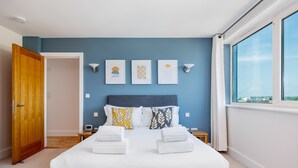 A bedroom with a large bed, a wooden wardrobe, a bedside table, and a window with a view. - Jeanneau - Dolphin Quays Development on Poole Quay (Poole)