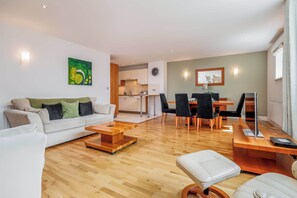 A modern living room with a sofa, coffee table, and dining area.