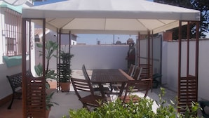 A patio with a table and chairs under a canopy, surrounded by potted plants. - Modern Villa, Private Pool, Wifi, Air Con, Central Location, Many Extras (Chiclana)