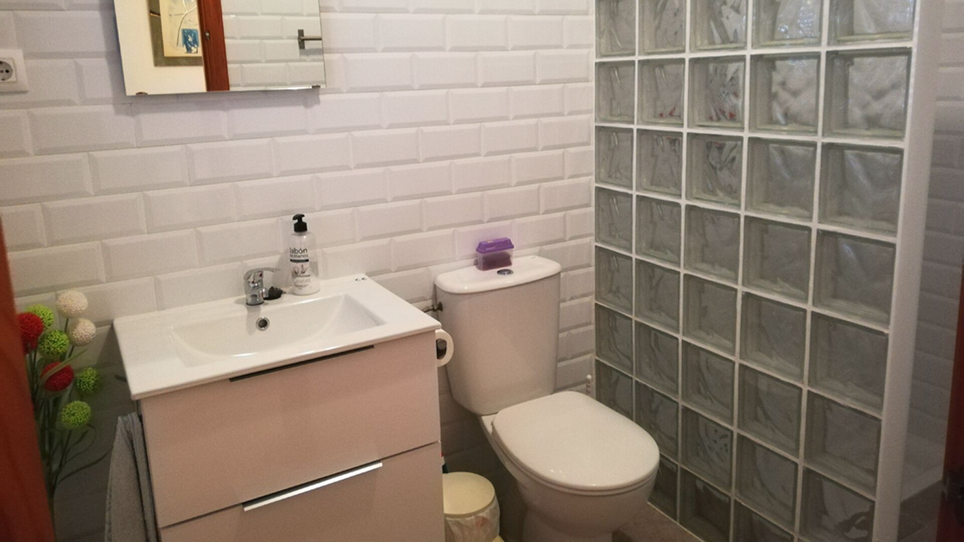 A bathroom with a white sink, toilet, and shower enclosure.