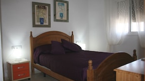 A bedroom with a wooden bed, purple bedding, a nightstand, and two wall-mounted paintings. - Modern Villa, Private Pool, Wifi, Air Con, Central Location, Many Extras (Chiclana)