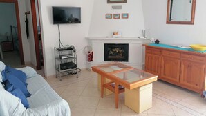A living room with a sofa, a coffee table, a TV, a fireplace, and a wooden cabinet. - Modern Villa, Private Pool, Wifi, Air Con, Central Location, Many Extras (Chiclana)