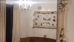 A mirror with an ornate frame reflecting a room with a chandelier, a brown sofa, and wall decorations. - Charming house surrounded by vineyards and the Luberon countryside (Grambois)