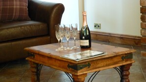 A wooden coffee table with a bottle of champagne and several wine glasses on it.