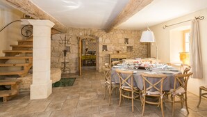 Ein rustikaler Essbereich mit einer Steinwand, einer Holztreppe und einem runden Tisch, gedeckt für eine Mahlzeit.