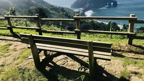 A wooden bench overlooking a coastal landscape with a rocky outcrop and ocean waves. - Country Cottage / Bilbao (Gordexola)