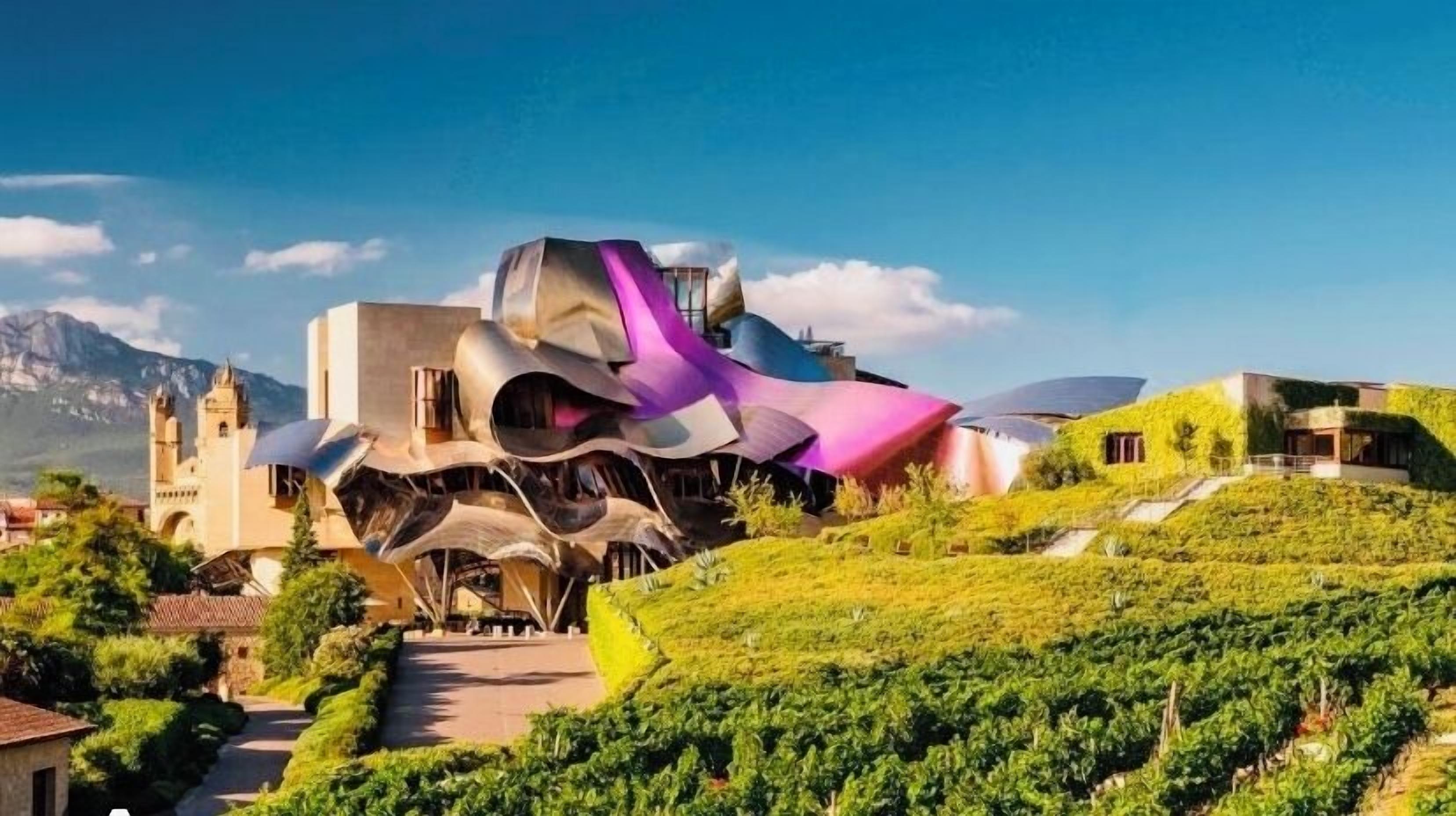 Um edifício moderno com design arquitetônico único, rodeado por vegetação exuberante e um vinhedo.
