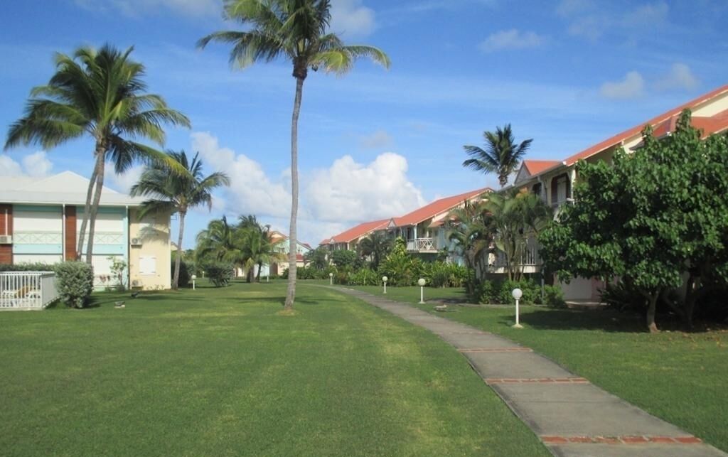 A row of hotel buildings with a well-maintained lawn and palm trees.