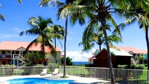 A pool area with two pools, surrounded by palm trees and a white fence. - Luxury residence on plage des raisins clairs in saint-francois (Saint-François)