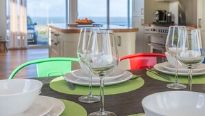 A dining area with a table set for four, including wine glasses and plates, in a modern kitchen with large windows.