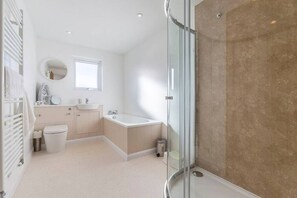 Ein modernes Badezimmer mit Duschabtrennung aus Glas, einer freistehenden Badewanne und einem Waschtisch mit Waschbecken und Spiegel.