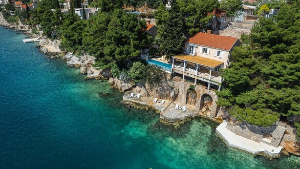 An aerial view of a coastal property with a swimming pool, a stone bridge, and a house with a red roof. - Extraordinary seafront villa with pool for up to 9 people (Lozica)