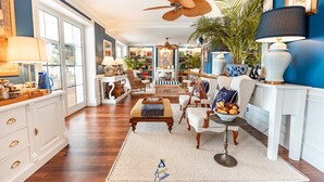 A spacious living room with a large window, a ceiling fan, a bookshelf, and a dining area with a table and chairs. - Extraordinary seafront villa with pool for up to 9 people (Lozica)