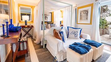 A bedroom with a canopy bed, a desk with a lamp, and a view of the outdoors.