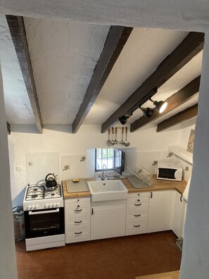 A kitchen with white cabinets, a stove, a sink, and a microwave. - Casita Escondida (Hidden Cottage) A private hidden gem with fantastic views... (Comares)