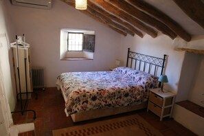 A bedroom with a bed, a window, a radiator, a hanging clothes rack, and a small bedside table. - Casita Escondida (Hidden Cottage) A private hidden gem with fantastic views... (Comares)