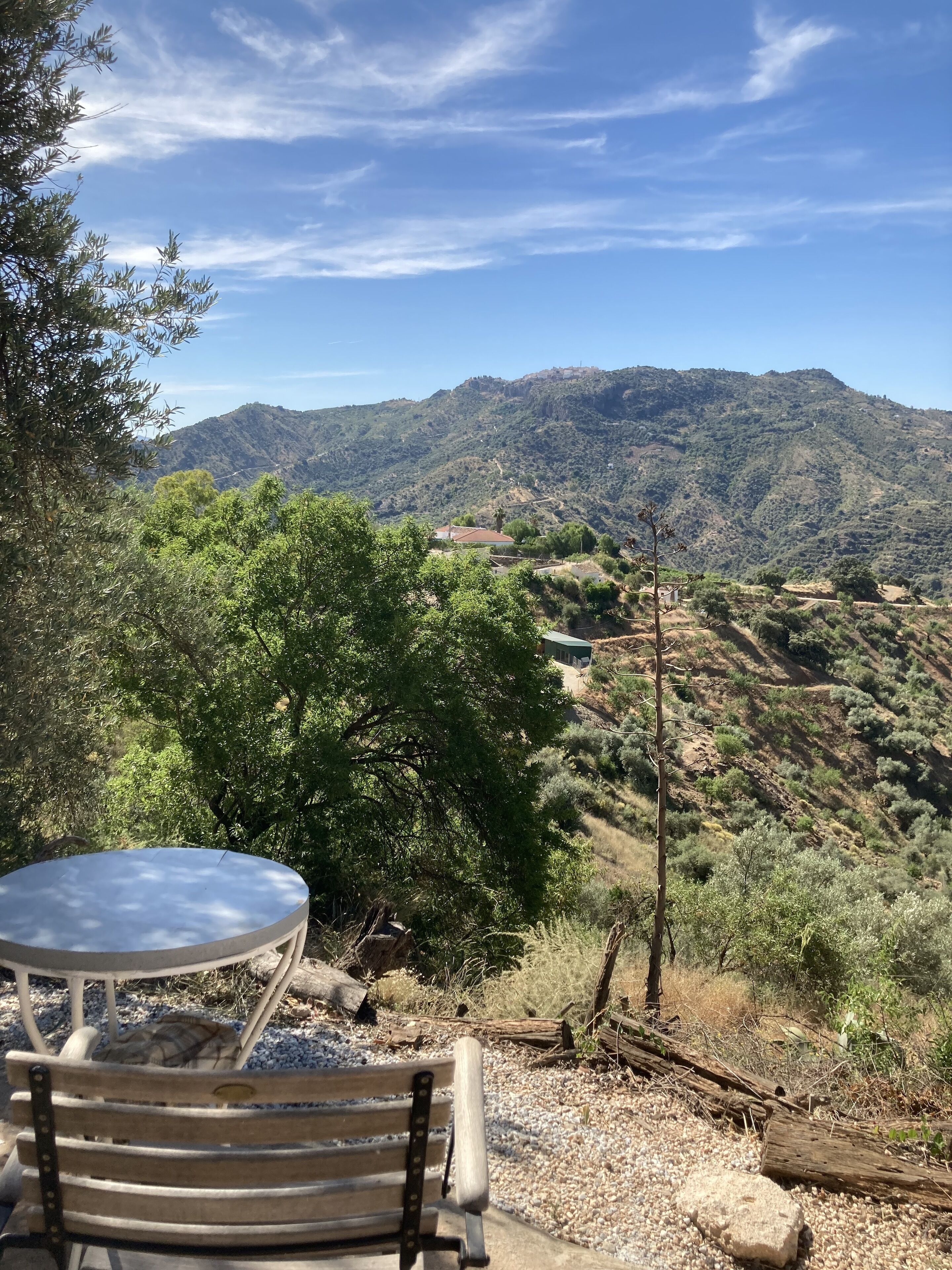 A table and bench in a natural setting with a view of a mountainous landscape.