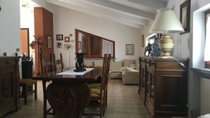 Un'ampia zona giorno con tavolo da pranzo, sedie, divano e lampada.