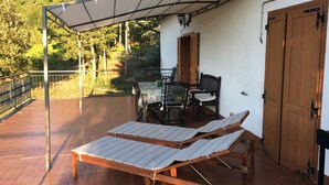 Un patio con due poltrone, un tavolo e sedie, e una porta in legno.