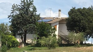 Una casa con pannelli solari sul tetto, circondata da alberi e un cielo sereno.