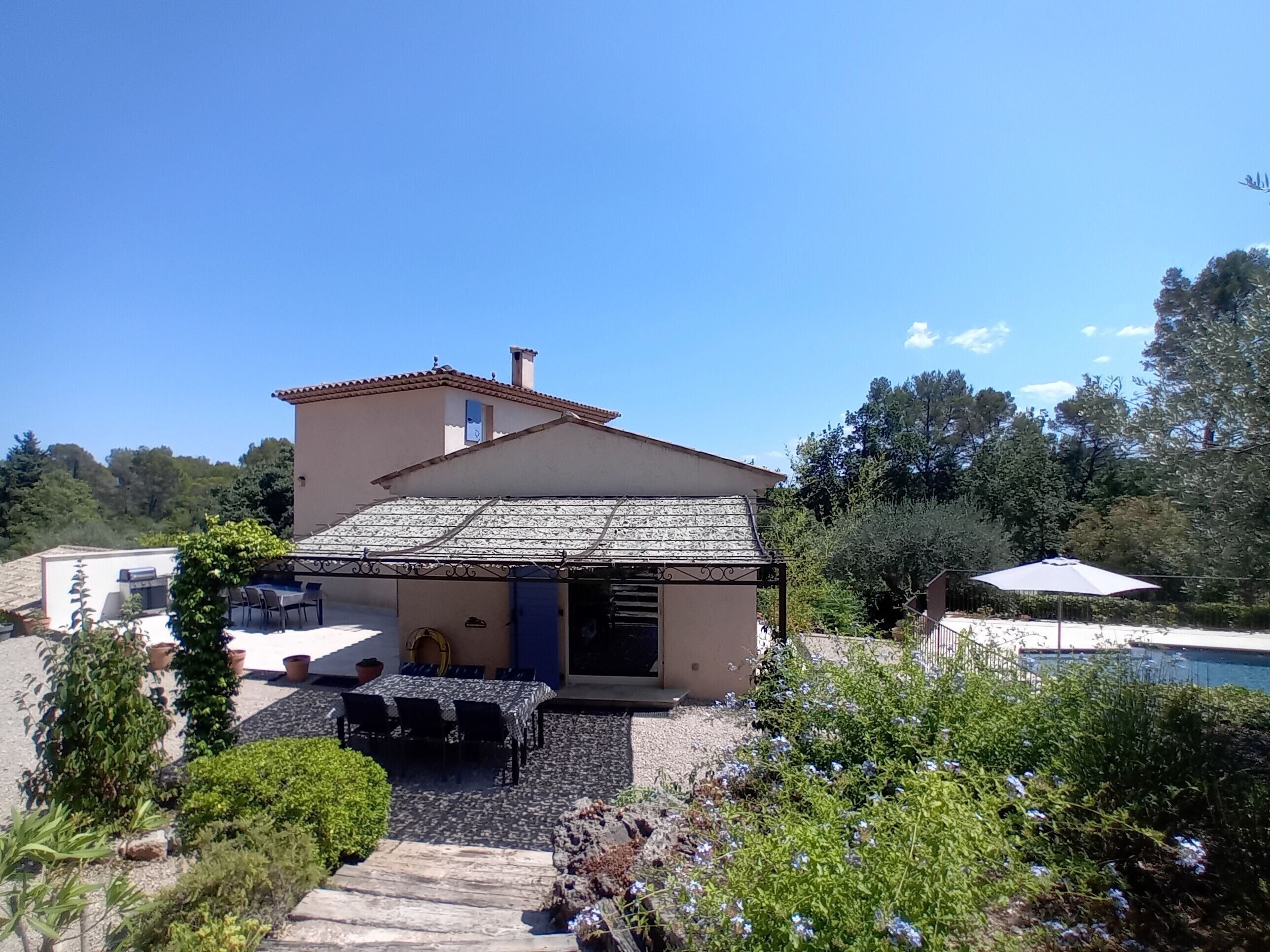 A house with a tiled roof, a patio with outdoor seating, and a swimming pool.