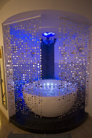 A circular water feature with a central column, surrounded by a perforated metal wall.