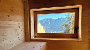 A wooden cabin with a window offering a mountain view. - Cozy Mountain Lodge (Roncegno Terme)