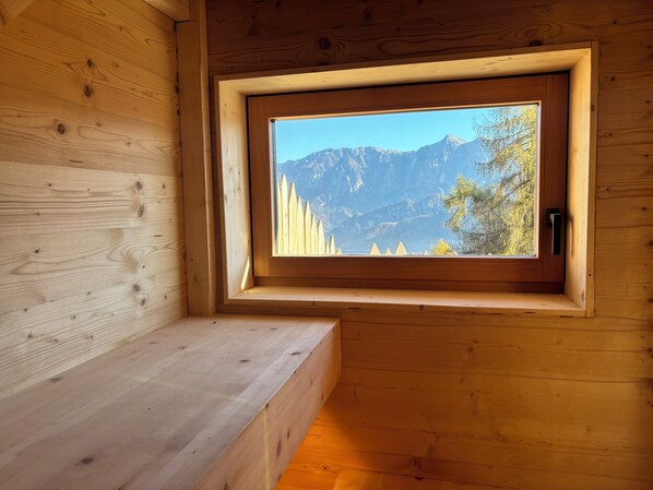 A wooden cabin with a window offering a mountain view. - Cozy Mountain Lodge (Roncegno Terme)