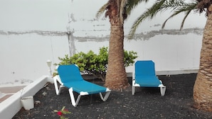 Two blue lounge chairs with white frames, positioned on a dark surface with a white wall in the background. - La Concha Beach. 2Dormitorios wifi and communal pools (Playa Honda)