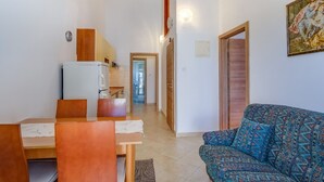 Un espace de vie compact comprenant un coin repas, un canapé, un réfrigérateur et un coin cuisine.