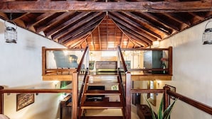 A wooden staircase in a rustic interior with a lofted upper level.