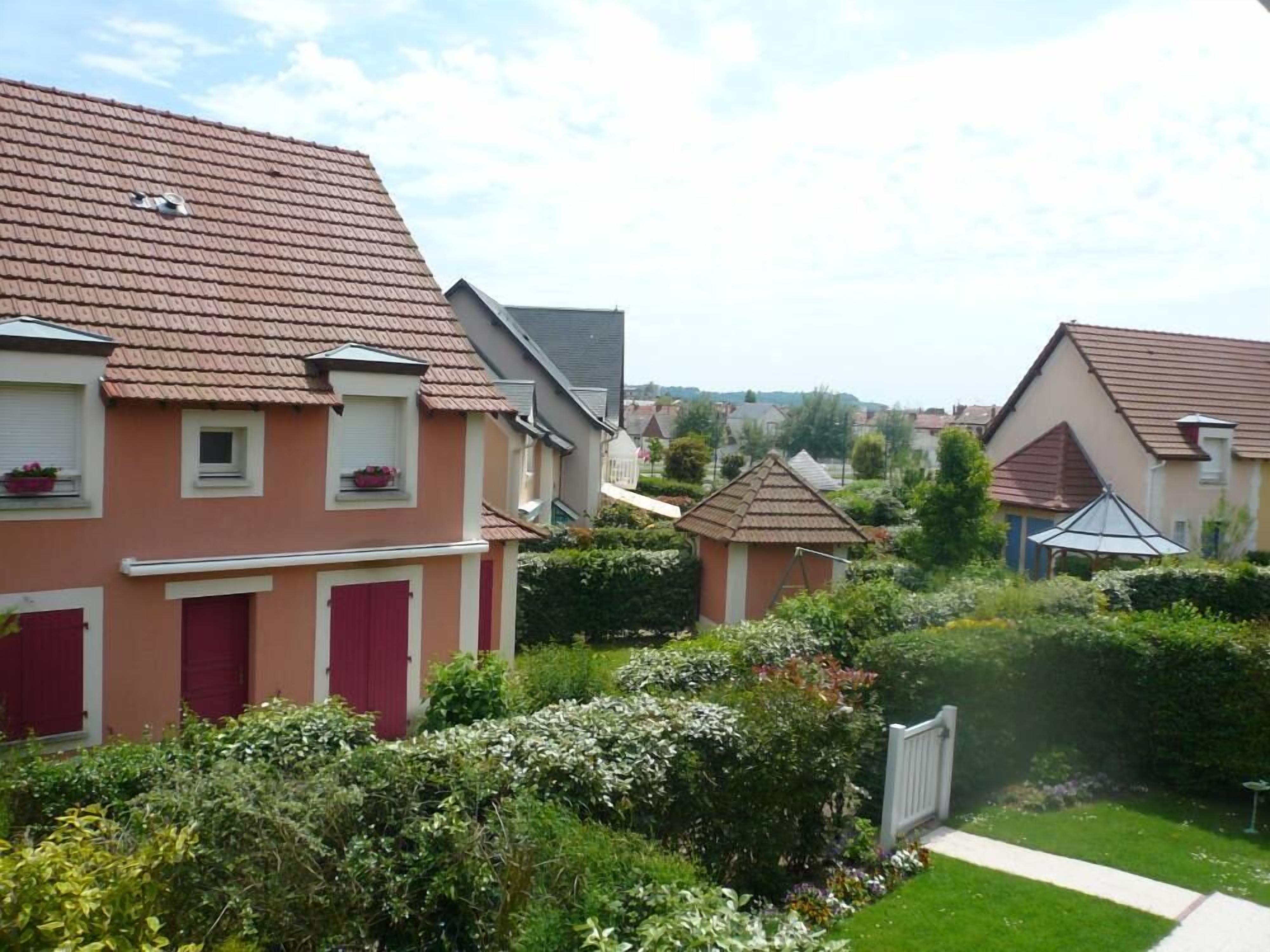 A row of houses with red-tiled roofs and a well-maintained garden in front.
