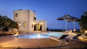 Una villa moderna con piscina, area relax esterna e vista sul mare.