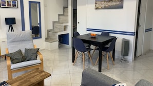 Un espace de vie compact comprenant un coin repas, un canapé, un banc, un escalier et une vue sur un port.