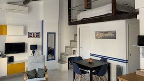 Un espace de vie compact comprenant une chambre en mezzanine, un coin repas et un coin salon.