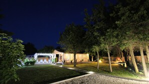 A well-lit outdoor area with a covered seating area, a pathway, and trees. - Beautiful house 20 meters from sea, free Wi-Fi (Peroj)