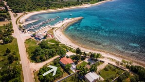 An aerial view of a coastal area with a marina, beach, and residential buildings. - Beautiful house 20 meters from sea, free Wi-Fi (Peroj)