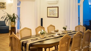 Ein Esszimmer mit einem großen runden Tisch, sechs Korbstühlen und einer Chandelier.