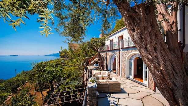 Eine Küstenvilla mit Steinarchitektur, Sitzgelegenheiten im Freien und Blick auf das Meer.