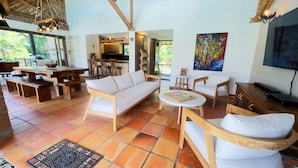 Un vaste espace de vie comprenant un canapé en bois, une table à manger et un téléviseur.