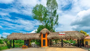 Une construction à toit de chaume, sur laquelle on peut voir des panneaux indiquant « Decameron » et « Cinco de Mayo ».