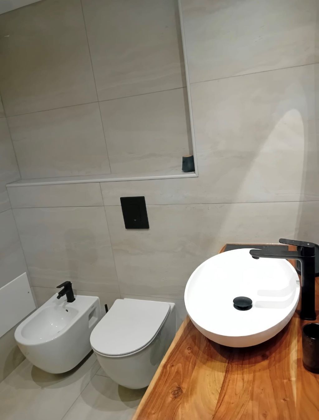 Une salle de bain moderne avec un lavabo blanc, un bidet et des toilettes.
