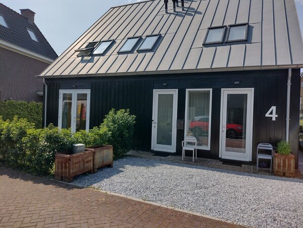 A modern building with a sloped roof, three large windows, and a number '4' on the facade. - 2 room studio with bathroom in city villa with free private parking (Amsterdam Nieuw-West)
