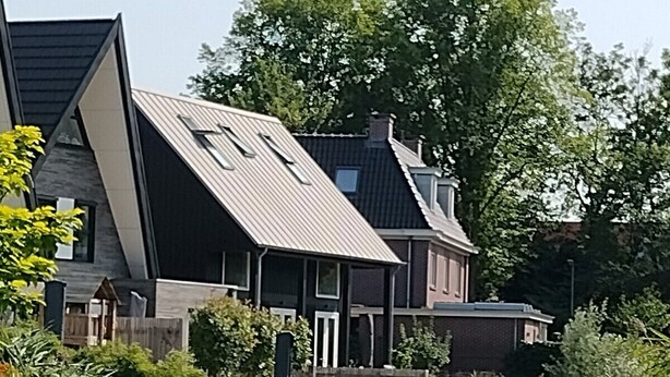 A house with a sloped roof and a wooden deck extending over a canal.
