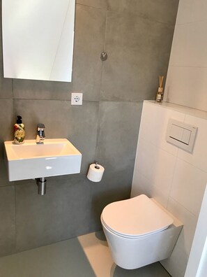Une salle de bain avec un lavabo blanc, des toilettes et un miroir.