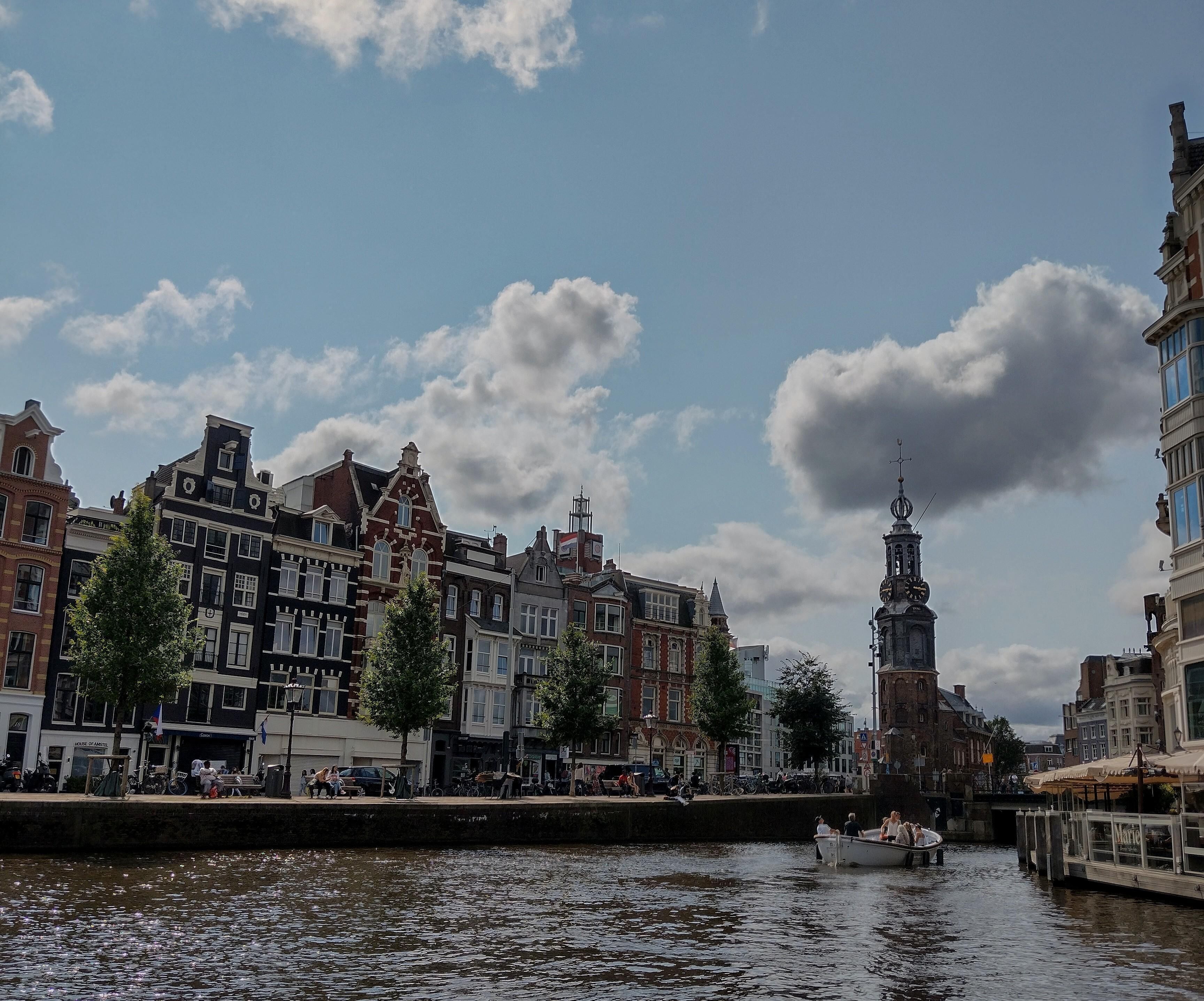 Een gracht met een boot, historische gebouwen en een toren.