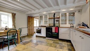 A kitchen with white cabinets, a wooden dining table, and a green chair.