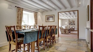 A dining area with a long table set for six, wooden chairs, and a blue tablecloth.