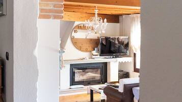 Ein gemütliches Wohnzimmer mit Kamin, Holzbalken und einer Chandelüster.