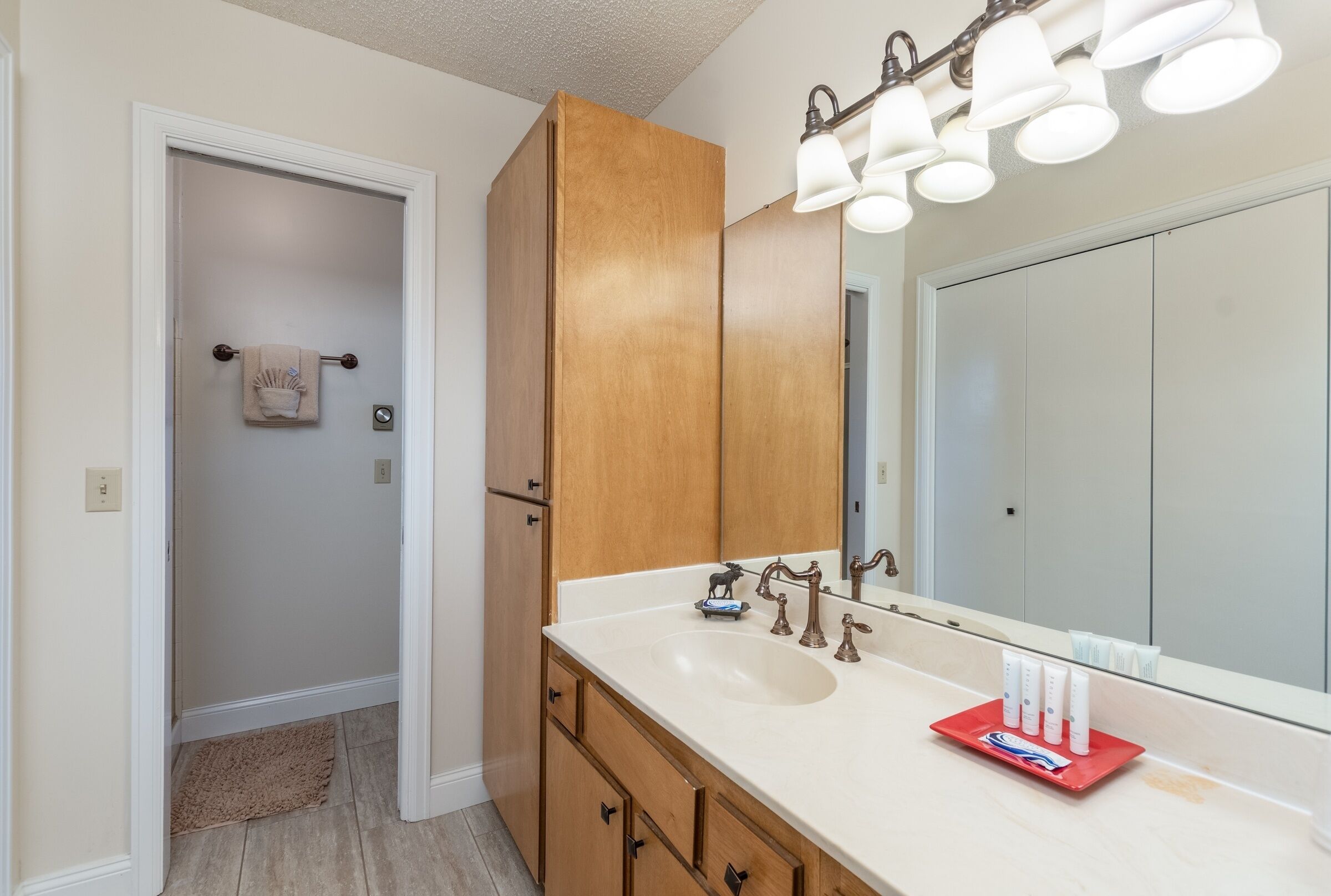 A bathroom with a double sink, wooden cabinets, a large mirror, and a towel rack.